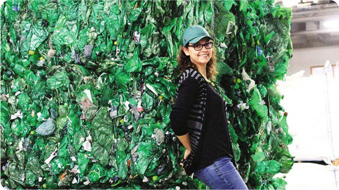 Woman leaning against a bundle of recycled plastic.
